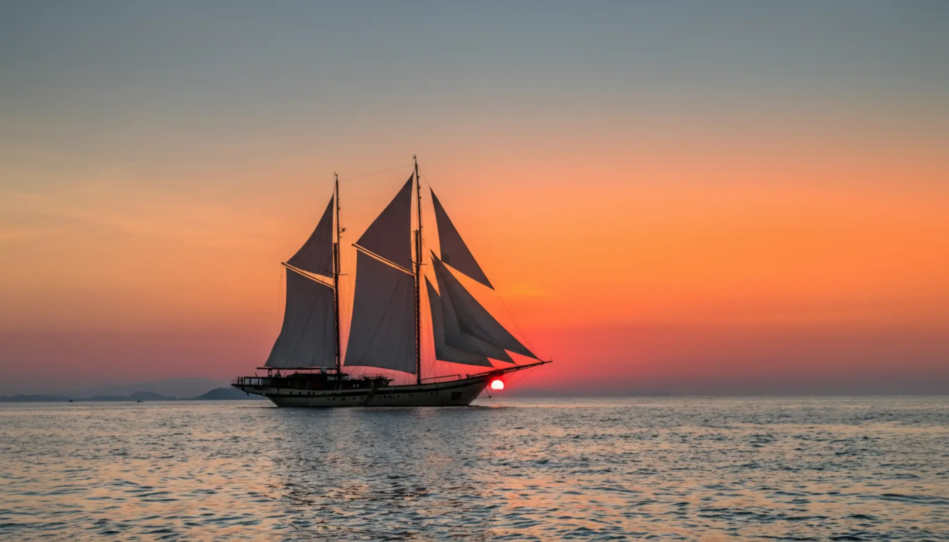 Luxury phinisi sailing yacht at sunset in Indonesian waters